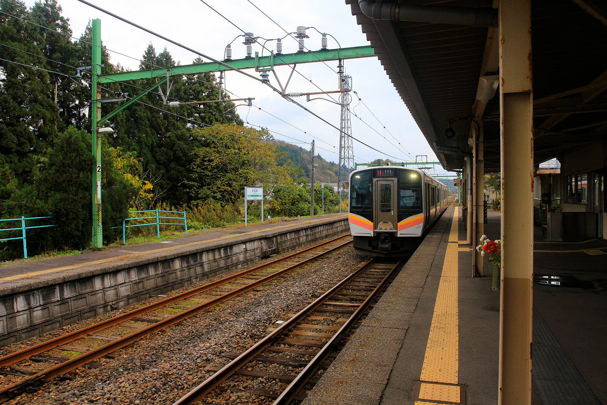 Serie 129, die neuen Triebzüge für die Präfektur Niigata (Japan, am Japanischen Meer). Einfahrt von Zug 129-105 im kleinen Dörfchen Izumozaki am Japanischen Meer. Man beachte den kleinen Blumenstrauss am Pfeiler des Bahnsteigdachs. 12.November 2018 