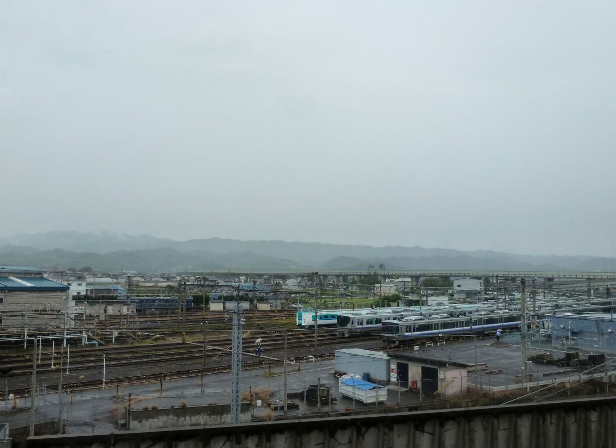 Serie 223: Was für ein Regenhimmel! Im Betriebswerk Hineno (direkt gegenüber dem Internationalen Flughafen Kansai) stehen (v.r.n.l.) ein klassischer S-Bahnzug Serie 223, ein neuer S-Bahnzug Serie 225, und ein Intercity mit neigbarem Wagenkasten Serie 381. 16.Juni 2011.  