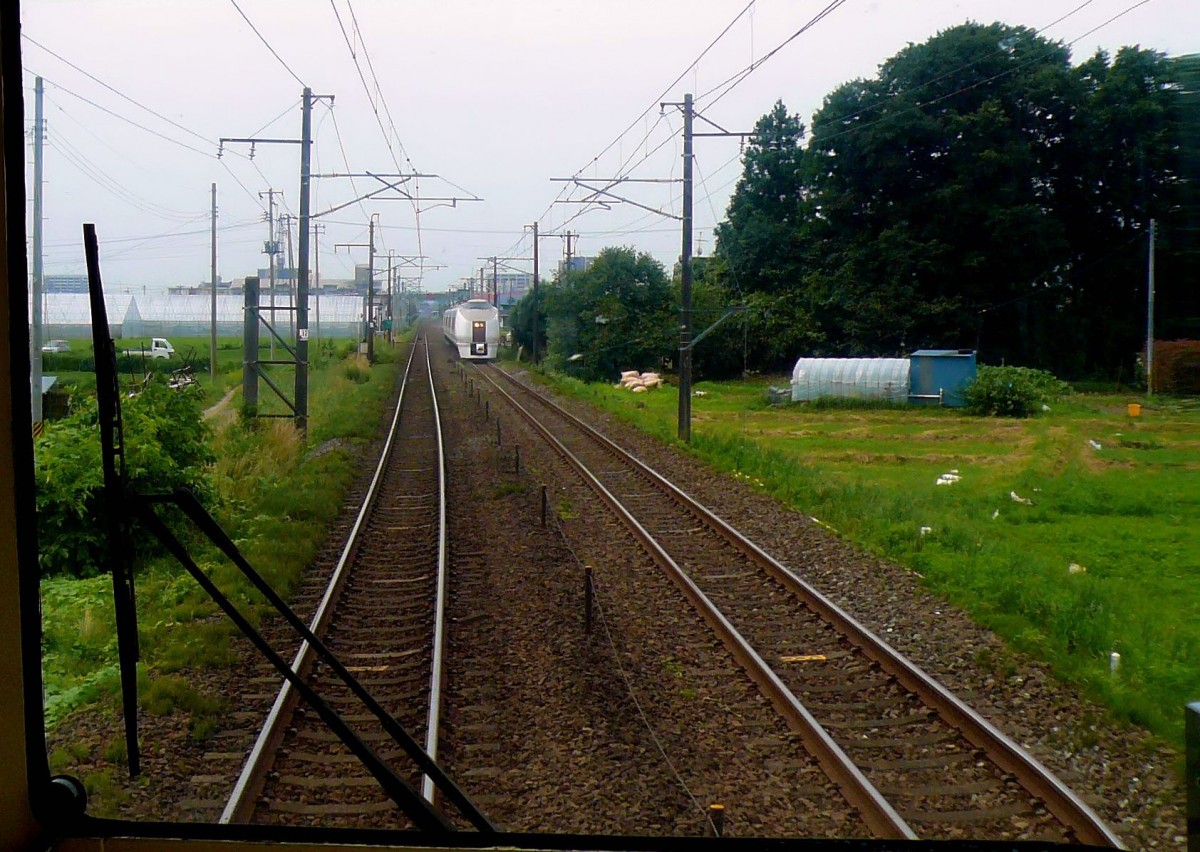 Serie 651: Hierher wird die Serie 651 wohl nie mehr gelangen, seit ihre Strecke der Pazifikküste entlang von Tokyo nach Sendai durch die Tsunami-/AKW-Katastrophen zerstört wurde. In Natori bei Sendai begegnet der Vierwagenteil des Zuges Nr.6. 11.Juli 2010. (Bild durch die verglaste Führerstandrückwand eines Gegenzugs)