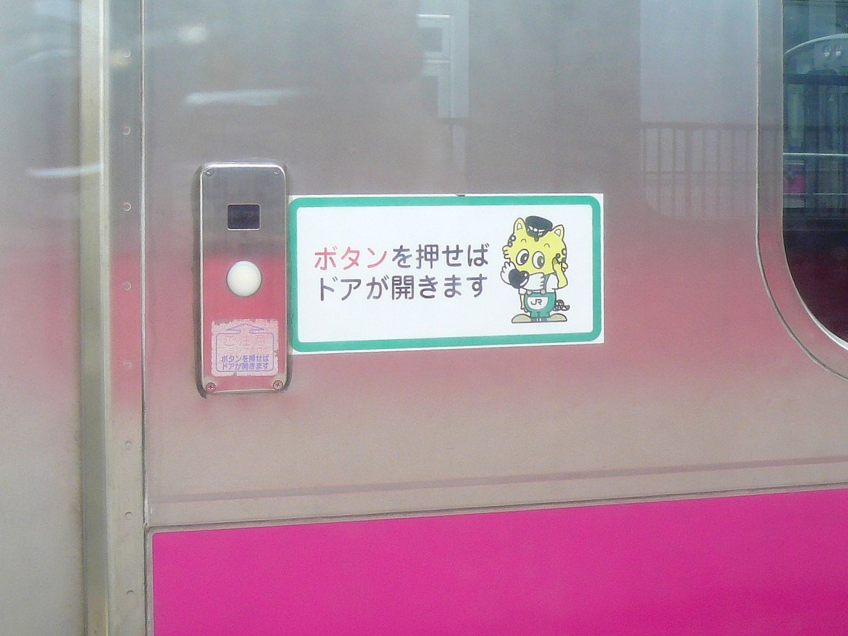 Serie 701 des Bezirks Akita: Grundsätzlich werden in Japan an allen Stationen alle Türen (der entsprechenden Seite) geöffnet. In kalten Gebieten werden jedoch heute die Türen von den Fahrgästen selbst bedient, so dass nur dann kalte Luft hereinströmt, wenn auch jemand ein- oder aussteigt. Das Bärchen an Zug 701-102 sagt:  Wenn Sie auf den Knopf drücken, dann öffnet sich die Türe . 10.Juli 2010. 