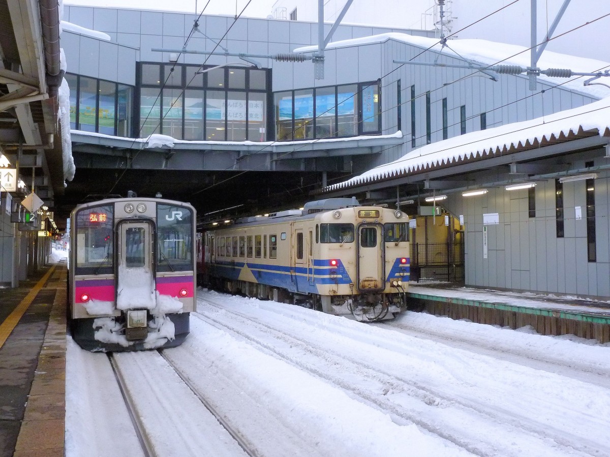 Serie 701 des Bezirks Akita - Begegnungen: Im Hauptbahnhof Akita wartet Zug 701-2 neben dem Dieselzug auf die Oga Halbinsel, geführt von KIHA 40 523. 12.Februar 2013. 