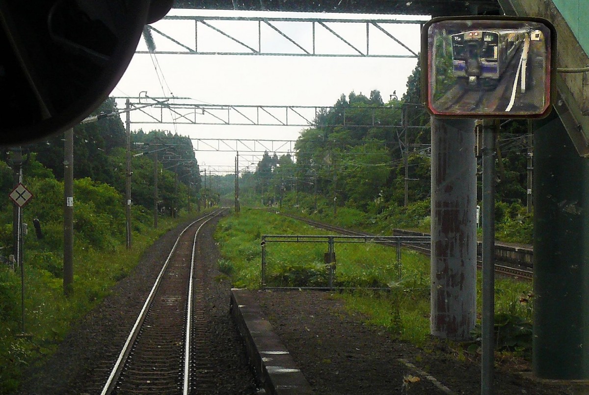 Serie 701 des Bezirks Morioka: In der feuchten und dicht von Wald umgebenen Station Karibasawa. Im ziemlich lädierten Spiegel ist Zug 701-1002 (heute Aoi Mori-Bahn 701-3) zu sehen, 5.Juli 2010. 
