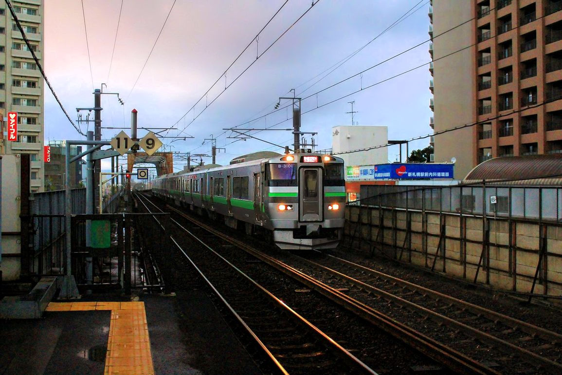 Serie 733, die neuen S-Bahnzüge für die Agglomeration Sapporo auf Hokkaidô. Zug 733-3101 nach einem heftigen Regenguss am späten Abend in Shin Sapporo, 30.September 2014. S-BAHN SAPPORO 