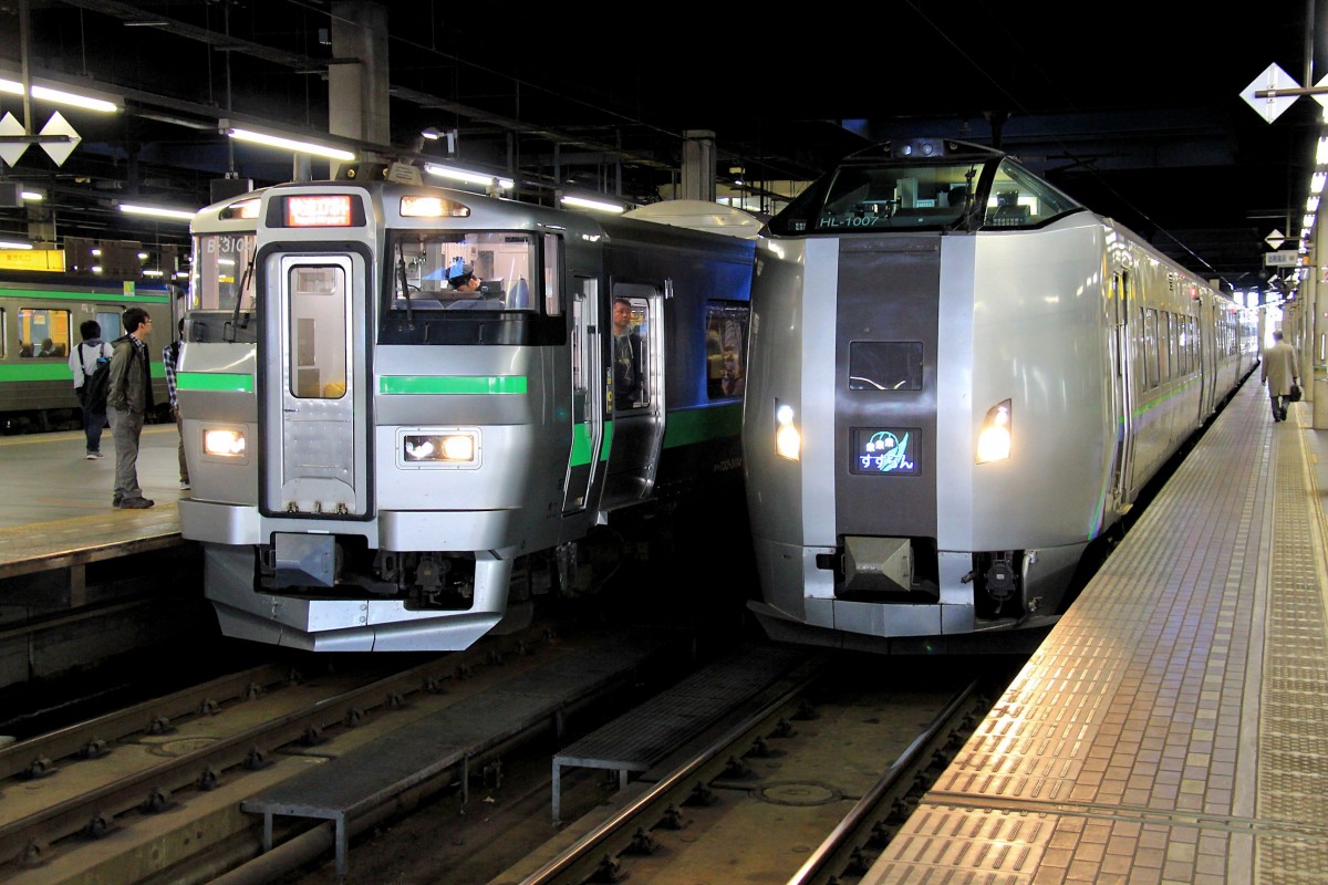 Serie 733, die neuen S-Bahnzüge für die Agglomeration Sapporo auf Hokkaidô. Sapporo Hauptbahnhof, links der S-Bahnzug 733-3104, rechts abfahrbereit der Intercity  Suzuran  ( Maiglöckchen ) (Zug 789-1007) in die Industriestadt Muroran an der Südküste von Hokkaidô. 23.Oktober 2015.   