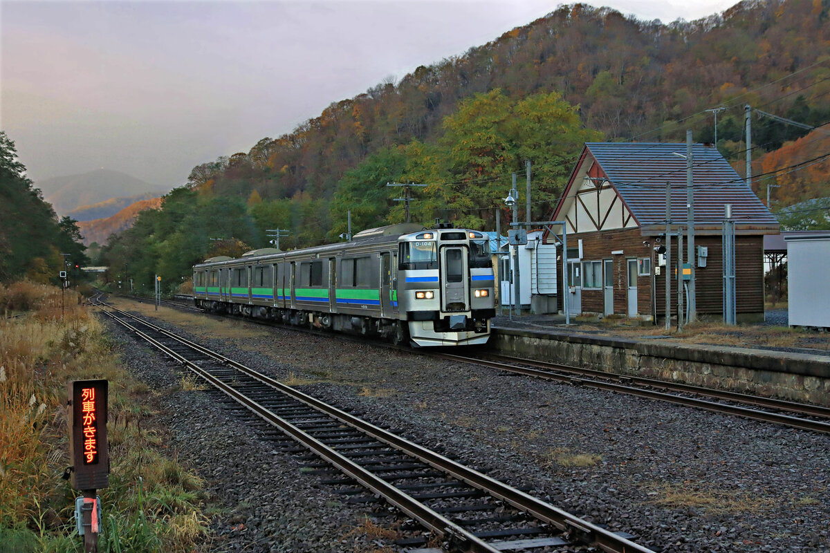 Shikaribetsu, an der alten Hauptstrecke über den Pass von Kutchan. Ganz früh am Morgen (und am Abend in der Gegenrichtung) kommt ein interessanter Zug der Serie KIHA 201 von JR Hokkaidô über diese Strecke. Dieser Zug wird nach Erreichen der Sapporo S-Bahn an einen fast gleich aussehenden elektrischen Triebwagen angekuppelt und dann als kombinierte elektrische und Diesel-Komposition in die Hauptstadt von Hokkaidô weiterfahren. Im Bild Zug KIHA 201-104 in Shikaribetsu, 29.Oktober 2022
