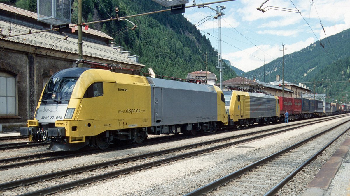 Siemens Dispolok ES 64 U2-048 (182 548) und ES 64 F4-XXX (189 XXX), vermietet an Lokomotion, sind mit einem KLV-Zug stromlos unter die italienische Fahrleitung gerollt (Bahnhof Brennero/Brenner, 30.06.05); digitalisiertes Dia.