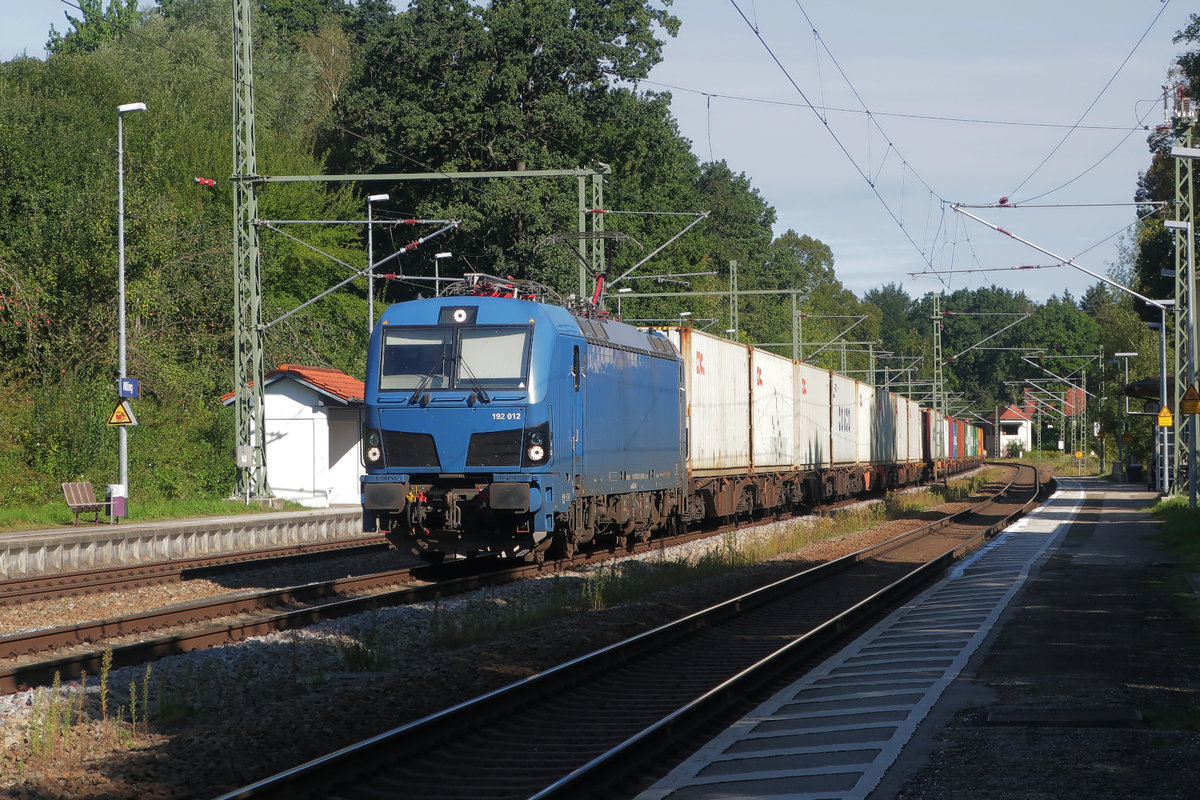 Smartron 192 012 durchfährt an einem Freitag-Vormittag den Bahnhof Aßling mit einem langen Zug, beladen mit Containern. Aßling ist einer der wenigen fotogenen Orte der Eisenbahn zwischen München und Rosenheim. Die Bahnsteige sind noch nicht erhöht, es gibt keine Schallschutzwände und vor allem: Zwischen dem eigenen Standort und dem Zug liegt stets noch ein Gleis. Fast überall sonst ist die Strecke  zugewachsen . 4. September 2020.