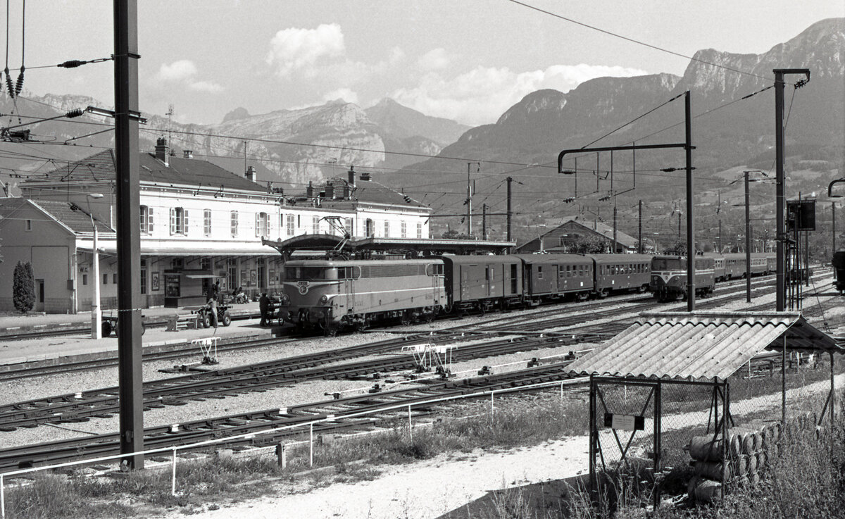 SNCF BB-25153 bei der Ankunft in La Roche-sur-Foron am 02.08.1976, mit Zug 5601 von Paris nach St. Gervais. Links das Bahnhofsgebäude aus der PLM-Zeit. Rechts wartet SNCF CC-25008. Scanbild 90785, Kodak Plus Xpan.