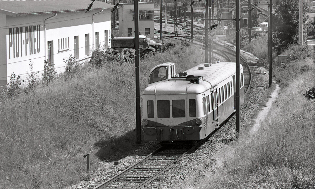 SNCF X3912 bei der Abfahrt aus La Roche-sur-Foron. Der  Autorail Picasso  ist auf seiner Stammstrecke auf dem Weg nach Annemasse, als Zug 8765. Im Hintergrund mittig erkennt man Stellwerk P2 am Bahnhof. Aufnahme am 02.08.1976, Scanbild 90784, Kodak Plus-Xpan.