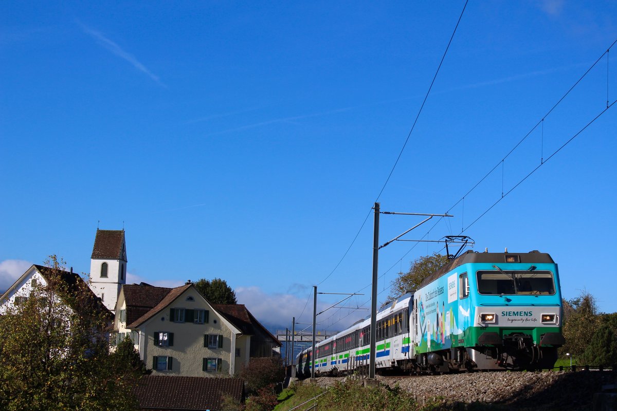SOB Werbelok Re 456 092  Siemens  am Morgen des 7. Oktober 2017 unter blauem Himmel mit dem VAE von Luzern nach St. Gallen in Bollingen, Richtung Schmerikon. Irgendwie erinnert mich die Gegend und das  Dörfchen  schon noch ein bisschen an St. Saphorin im Kanton Waadt. 
