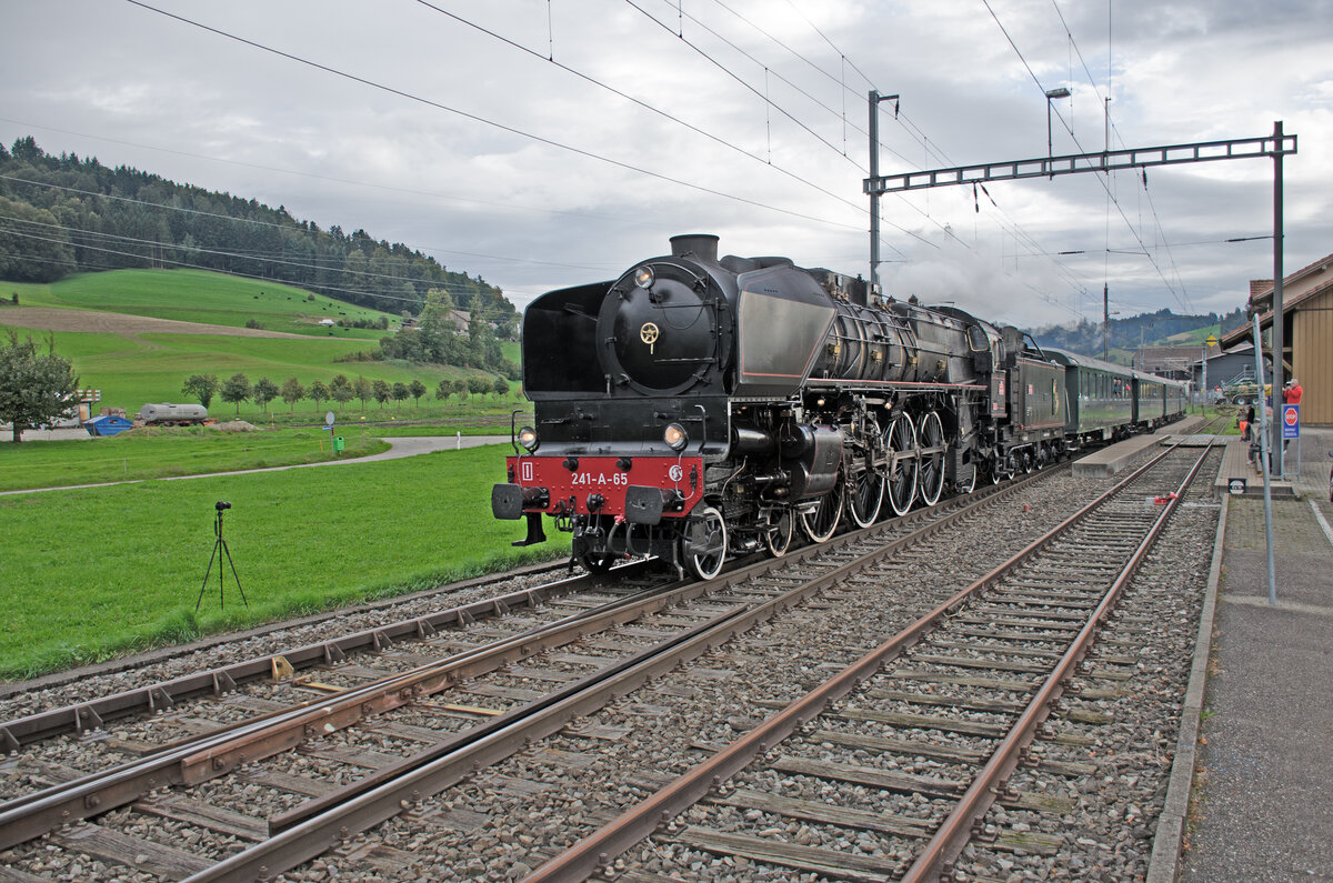 Sonntag den 06.10.2024 um 17:13 Uhr in Madiswil (BE) im Quartierteil Lindenholz (BE). Im Bahnhof Lindenholz fährt soeben der Dampfzug von Huttwil nach Koblenz (CH) fahrend mit der SNCF Dampflok 241-A-65 (Verein Dampflok-Depot Full) durch den Bahnhof Lindenholz. Der Zug hat etwas Verspätung was jedoch keinem Bahnfreund etwas antut. Die Typenbezeichnung lautet in der Schweiz A 4/7, in Deutschland 2-D-1, in Frankreich 241 und in England/Amerika 4-8-2 (bezeichnet als  Mountain -Bauart, welcher Name auch in Frankreich geläufig war). Die UIC Nummer der Dampflok lautet: 90 85 0041 065-3 CH-DDF. Auslöser für die Fahrt sind die Huttwiler Dampftage. Am Zugschluss befindet sich die EBT Be 4/4 Nr. 102. Ob sie als  Angstlok  dient lassen wir mal dahingestellt. Koordinaten GMS (Grad, Minuten, Sekunden): N 47° 9’ 18.3’’ O 7° 47’ 26.4’’