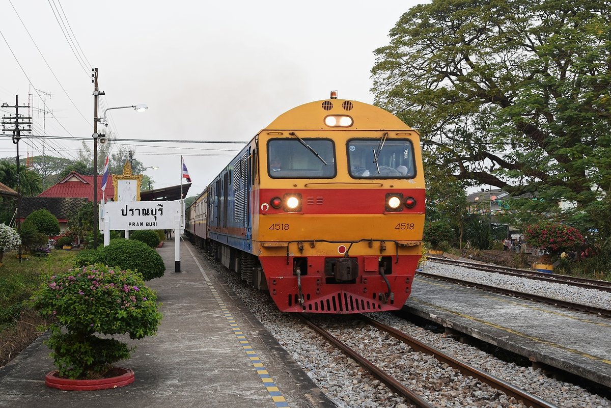SRT 4518 mit Rap 171 Bangkok Hua Lampong - Sungai Kolok durchfährt in der Abenddämmerung des 17.02.18 den Bahnhof Pran Buri.