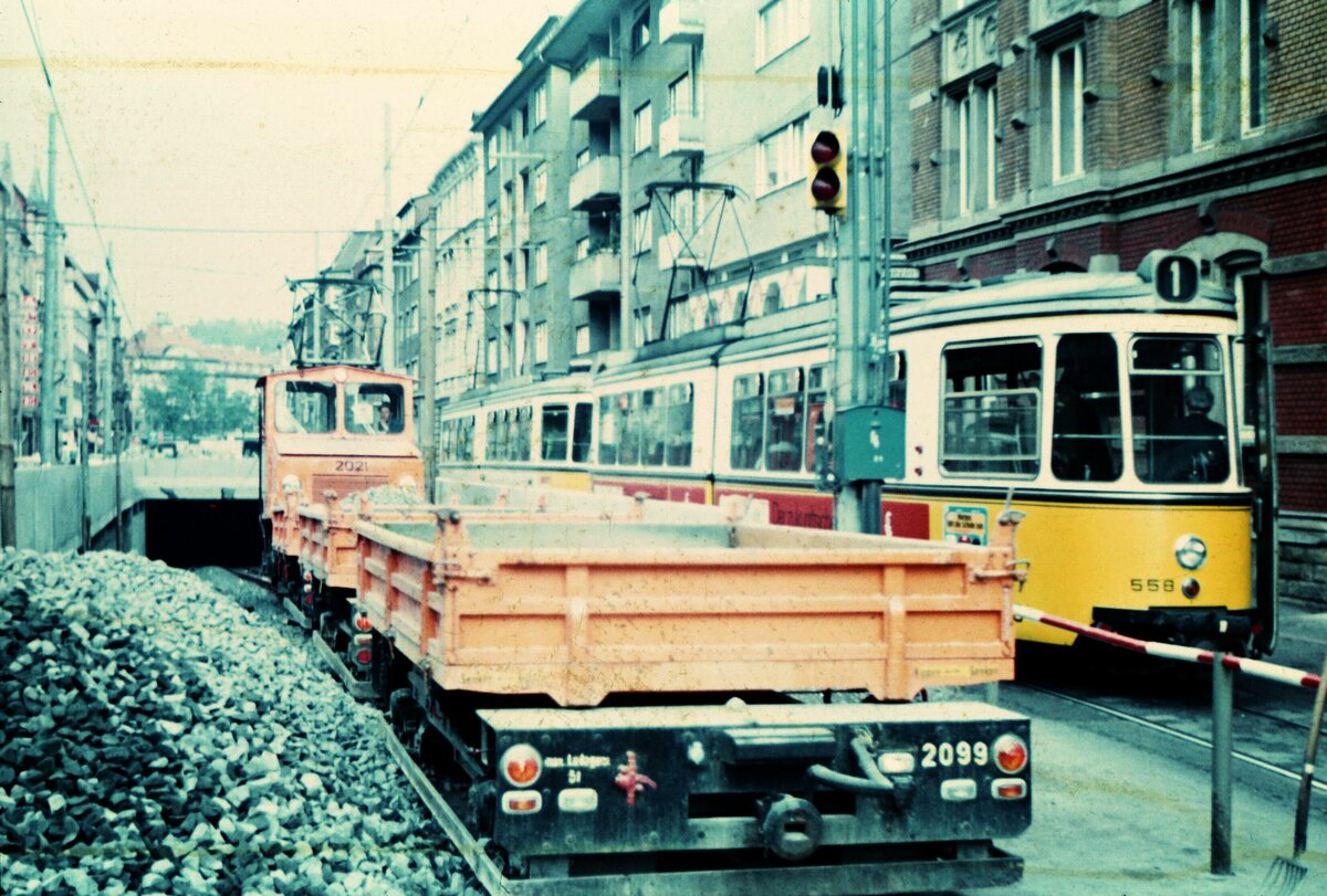 SSB Stuttgart__Arbeitsfahrzeuge der SSB in den 70er und 80er Jahren. A-Lok 2021 [ME/BBC 1946; +1995] mit drei Kipploren (am Schluß Nr.2099; 1970 mit UG ex Bw 1373; 2000 Vk an EVAG Essen] an der Tunnel-Rampe in der Böblinger Straße zum Marienplatz. Nicht mehr lange fuhr die Straßenbahn (hier GT 4 Nr.558; ME 1960; +1991 auf Linie 1) oberirdisch via Marienplatz ins Stadtzentrum. Bereits am 10./11.07.1971 fanden die öffentlichen Eröffnungsfahrten im Tunnel zwischen Marienplatz und Staatsgalerie statt. Ab Sept. 1971 gings durchgängig nur noch unterirdisch.__06-1971