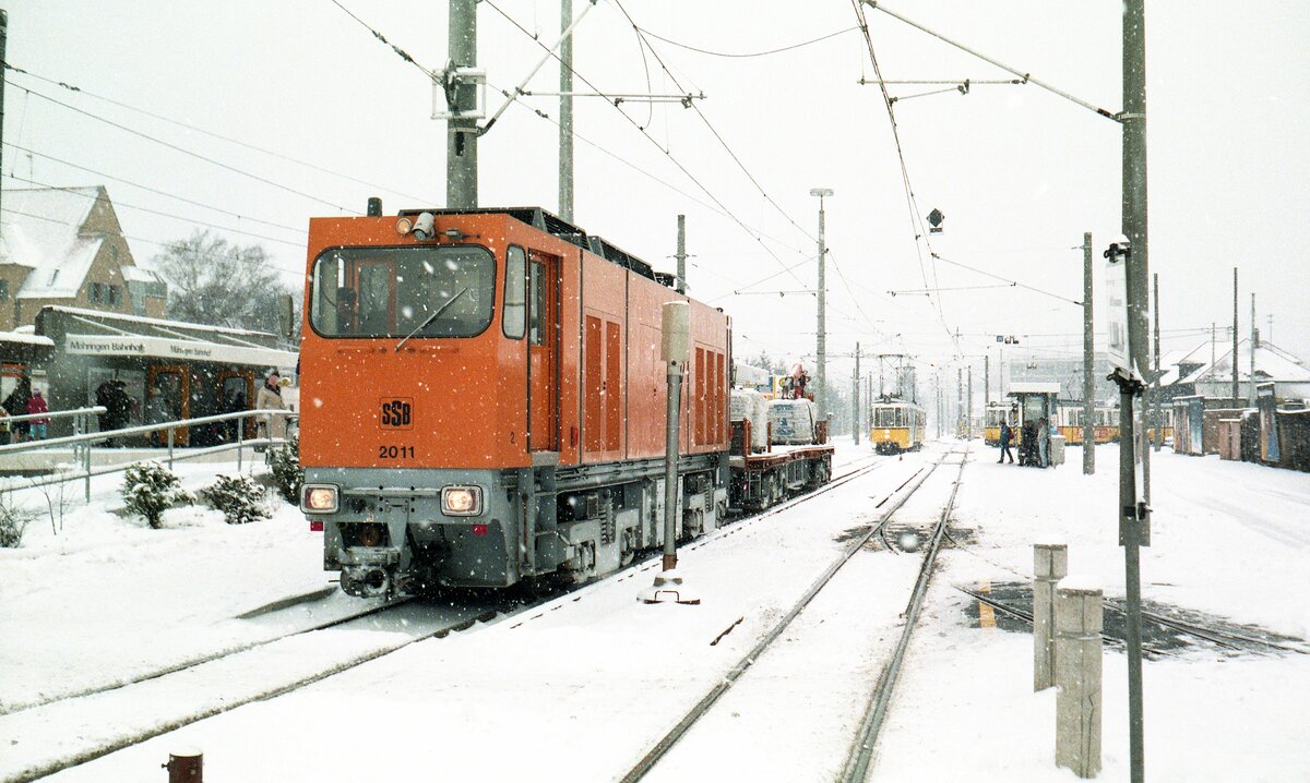 SSB Stuttgart__Arbeitsfahrzeuge der SSB in den 70er und 80er Jahren.  Es war Winter in Möhringen...  Die 4x E-DE-Lok 2011 [Bj.1981; Kaelble-Gmeinder/Siemens] rangiert mit ihrem 4x-Anhänger im Bahnhofsbereich S-Möhringen. Der 6er von Echterdingen wartet geduldig, bis er vorrücken kann.__22-12-1986