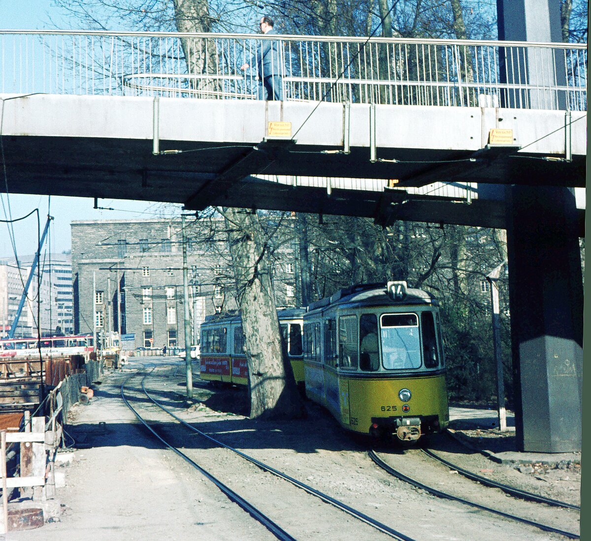 SSB Stuttgart__Gleis- und Tunnelbau__Das war der Blick zum Hauptbahnhof von der Schiller-/Neckarstr. unter der Fußgängerbrücke zwischen dem Oberen (links) und Mittleren Schloßgarten (rechts) hindurch. Der 14er mit GT4 625 fährt Slalom um einen der uralten Parkbäume. (Wenn ich googlemaps richtig interpretiere, könnte diese Platane eine der wenigen sein, die die S21  Rodungsaktion  in der Nacht des 1.Oktober 2010 überlebt haben).__1970