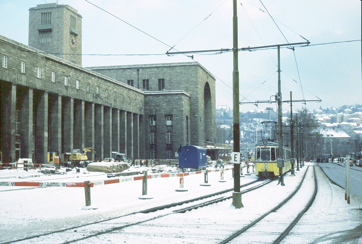 SSB Stuttgart__Gleis- und Tunnelbau__Linie 15 Richtung Zuffenhausen passiert vorm Hbf die Baustelle für das Tiefgeschoß und (noch eins tiefer) für die Stadtbahnhaltestelle der Linien vom Schloßplatz Richtung Pragsattel und die Linien vom Berliner Platz zur Neckarstr. Richtung Stöckach, sowie (noch eins tiefer) die querende S-Bahn Schwabstraße-S-Vaihingen.__01-12-1973