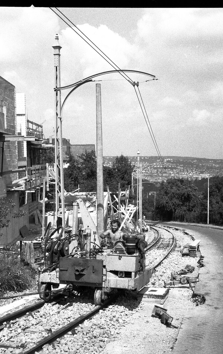 SSB Stuttgart__Zahnradbahn__Juli und August 1980 wurde die Bahntrasse für die neuen ZT4 Tw modernisiert. Dieses Gefährt kam auch ohne Zahnstange zurecht: die Gleisstopfmaschine hängt mit dem Drahtseil am Bagger.__08-1980 