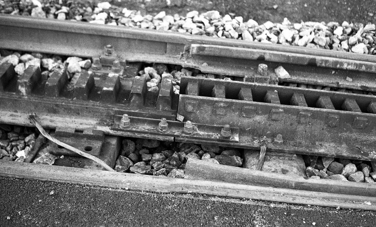 SSB Stuttgart__Zahnradbahn__Übergang von der talwärts bereits im Vorjahr eingebauten  Riggenbach light -Zahnstange (noch auf Stahl-Schwellen) auf die damals aktuelle Bauform der gefrästen Vollschiene. (Man vergleiche mit dem Foto an gleicher Stelle von 06-1976 mit bergseits noch 'original Riggenbach'). Ab den 1980er Jahren wurden im SSB Gleisbauhof aus Breitkopfschienen gefräste Zahnstangen selbst gefertigt. Eine Weiterentwicklung kam um das Jahr 2003 vom Technischen Büro des SSB Unternehmensbereichs Gleisbau: Herstellung der Zahnstangen aus der serienmäßig lieferbaren Vollschiene S49. Einziger Bearbeitungsschritt = Einfräsen der Zahnprofile in eigener Werkstatt bzw. durch Fremdvergabe. [Quelle:  Über Berg und Tal  4/2017]__05-11-1977