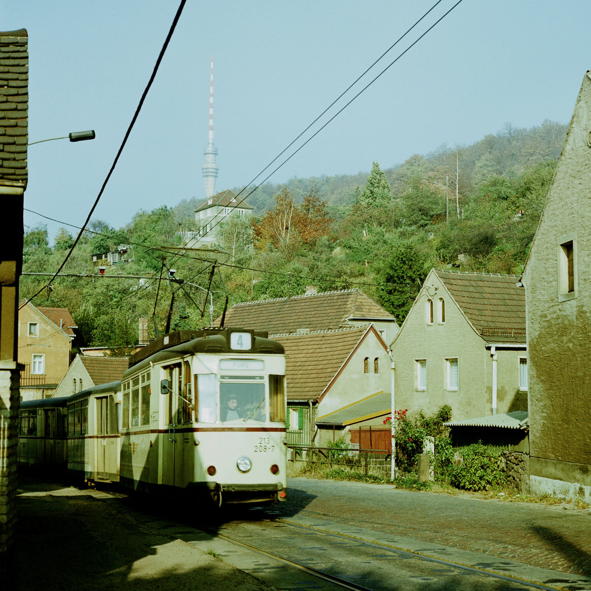 Straßenbahn Dresden, am 21. Oktober 1984 fährt die Straßenbahn auf der engen, hügeligen und kurvigen Pillnitzer Landstraße zum Endpunkt Pillnitz. Hier geht es in Wachwitz gerade über eine Kuppe. Im Hintergrund der Fernsehturm mit seinem damals noch gut besuchten Turmcafè.