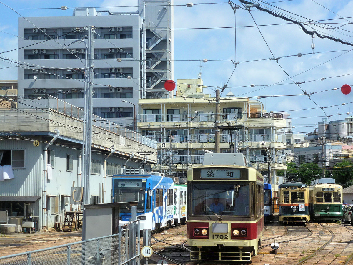 Strassenbahn Nagasaki, Serie 1700: Wagen 1702 im Betriebshof, umgeben von einem bunten Gemisch alter und neuerer Wagen. 8.August 2013 