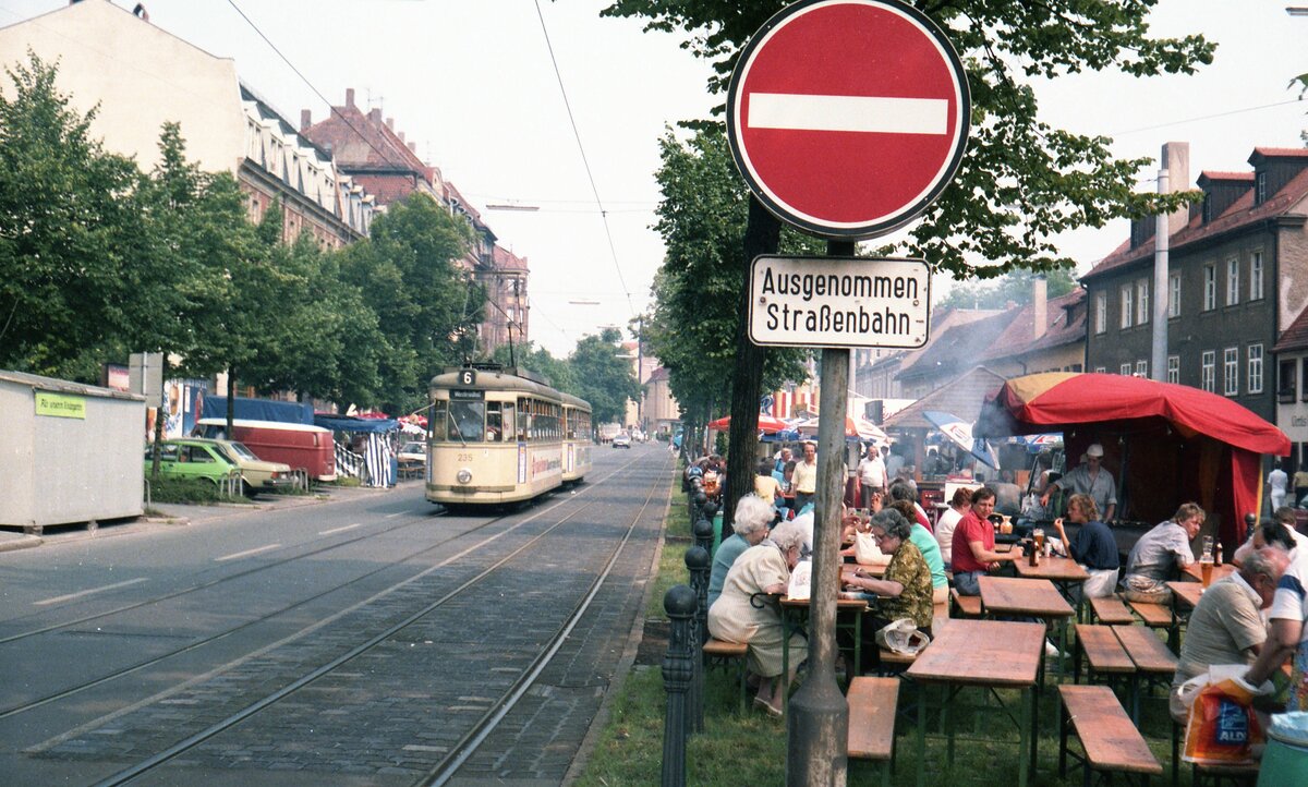 Straßenbahn Nürnberg__4x-Zug der Linie 6 mit Tw 235 [T4; MAN,Siemens; 1958; 1997 nach Braila] vom Westfriedhof kommend passiert den  Biergarten  der Kärwa-Besucher entlang den Gleisen in Johannis.__06-1986