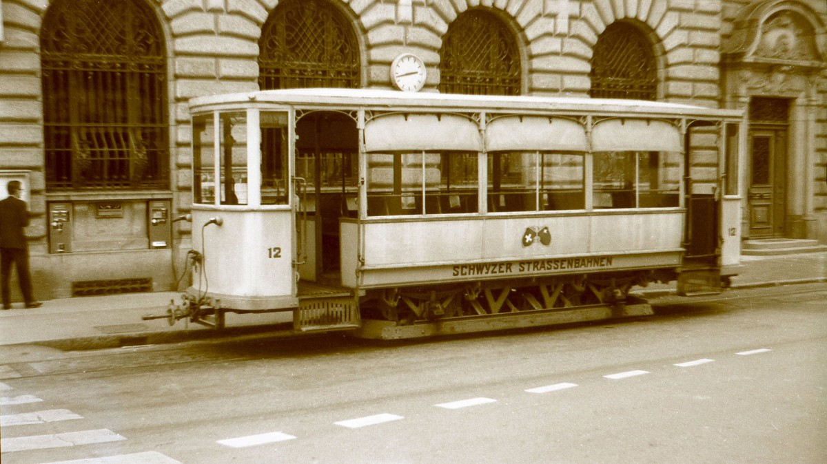 Strassenbahn Schwyz - Brunnen: Anhänger 12 mit dem Schweizerwappen und dem Schwyzerwappen; neben der Post in Schwyz. Oktober 1963. 