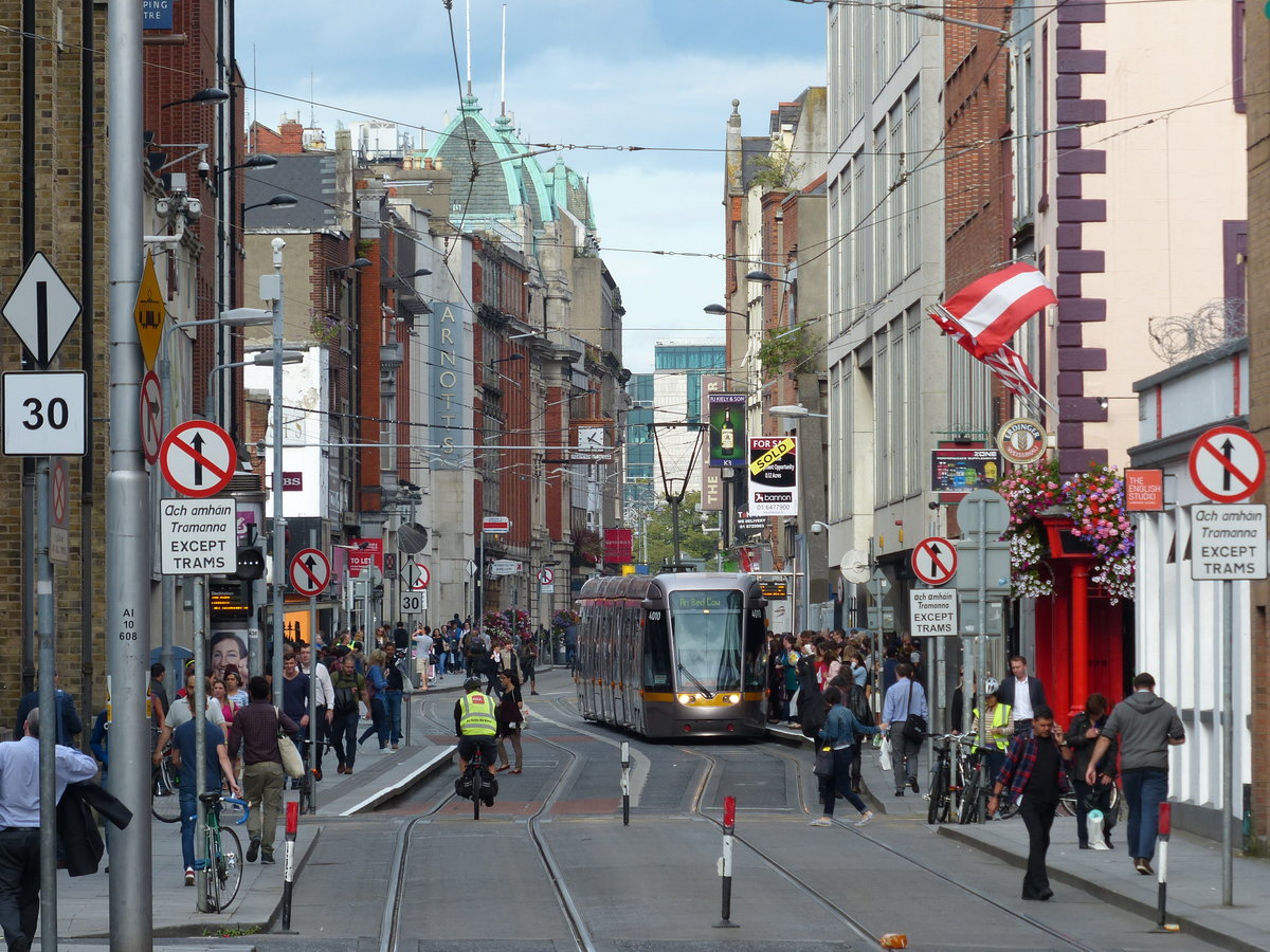 Straßenbahn im städtischen Getümmel der Abbey Street. Hier liegt das Einkaufsviertel der Stadt. Es ist nicht klar zu erkennen, ob die Menschengruppe tatsächlich einsteigen will - nach meiner Beobachtung sind die Bahnen auf dieser Strecke oft stark überfüllt. 2.8.2017, Dublin