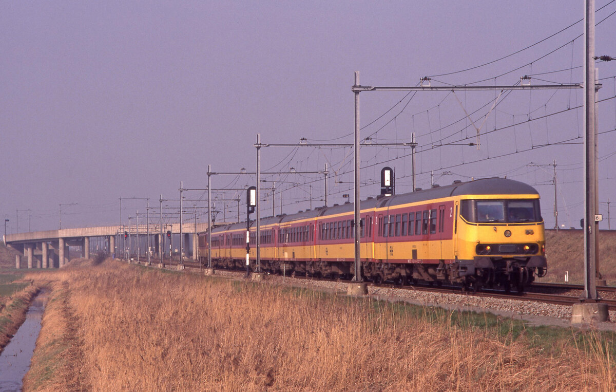 Streckenbild des Beneluxzuges Int-635 (Amsterdam CS - Brussel Zuid) bei Lage Zwaluwe am 14.03.1999, 13.54u. Es führt NS Steuerwagen 50.84.2870.112-4 -/- NMBS lok 1186 schiebt. Scanbild 7819, Fujichrome100.
