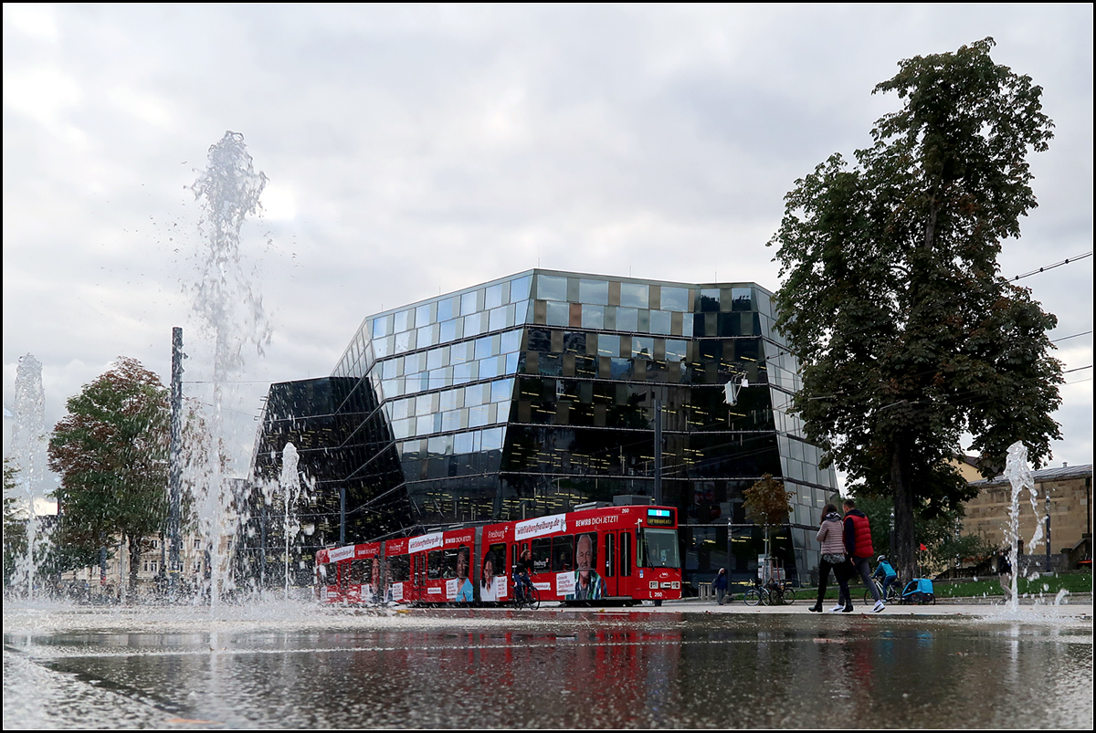 Streckendokumentation zweite Nord-Süd-Strecke in Freiburg - 

Harmonisch fügt sich Straßenbahn in den Platz der Alten Synagoge ein. Im Hintergrund der Kristall der Uni-Bibliothek.

07.10.2019 (M)