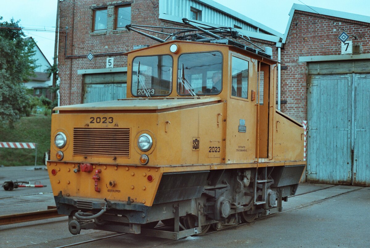 Stuttgarter Straßenbahnen (SSB): Bauzuglokomotive 2023 (MF Esslingen und BBC 1946) vor dem Möhringer Wagenschuppen der früheren Filderbahn, der von der SSB nur noch wenig genutzt wurde (1983 ?). Die Lokomotive des Typs  Bern  wurde zunächst bis 1948 für die Trümmerbeseitigung in der Stadt Stuttgart eingesetzt ( Trümmerlok ) und gelangte dann 1949 zur SSB, welche sie bis etwa 1994 als Bauzuglok nutzte. Sie ist in der Straßenbahnwelt Stuttgart erhalten. 