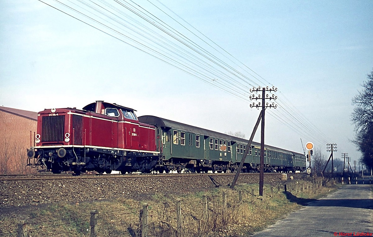 Südlich von Lingen ist eine 212 mit einer für die damalige Zeit typischen Wagengarnitur in Richtung Rheine unterwegs (Februar 1975)