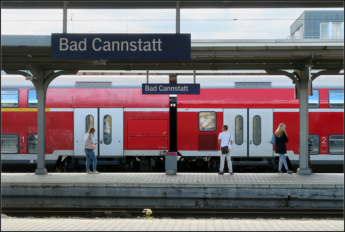 Symmetrie/ Asymmetrie -

Bahnhofsdach, das mittlere Bahnhofsschild und die Position des Zuges sind gemeinsam symmetrisch angeordnet. Aufgebrochen wird die Symetrie durch die Anordnung der drei! Bahnhofsschilder zu einander, der vier! Personen und dem Gebäude oben rechts. Auch die beiden Dosto-Wagen sind unterschiedlich.

Ein Draufhalten-und-Abdrücken-Motiv an dem ich nicht vorüber kam.

Stuttgart-Bad Cannstatt, 13.09.2019 (M)