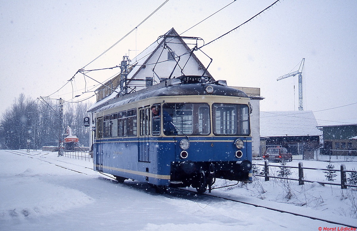T 6 der Trossinger Eisenbahn im Februar 1991 auf dem Abfahrtsgleis gegenüber des Staatsbahnhofes Trossingen (Strecke Rottweil - Villingen). Die Trossinger Eisenbahn wurde 1898 eröffnet und verband die Mundharmonikastadt Trossingen mit der etwa 4 km entfernten Staatsbahn. Wegen der starken Steigungen wurde sie von Anfang an elektrisch betrieben und stellt damit bis heute einen Inselbetrieb dar. Seit der Eröffnung des  Ringzugbetriebes  2003 verkehren auf der Strecke Regio-Shuttle der HzL, elektrische Fahrzeuge werden nur noch bei Sonderfahrten eingesetzt.