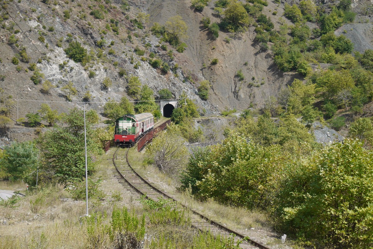 T669.1054 hat mit dem aus zwei Wagen ostdeutscher Produktion bestehenden Zug 19 Librazhd - Durres den Tunnel westlich von Librazhd verlassen (6.9.14).