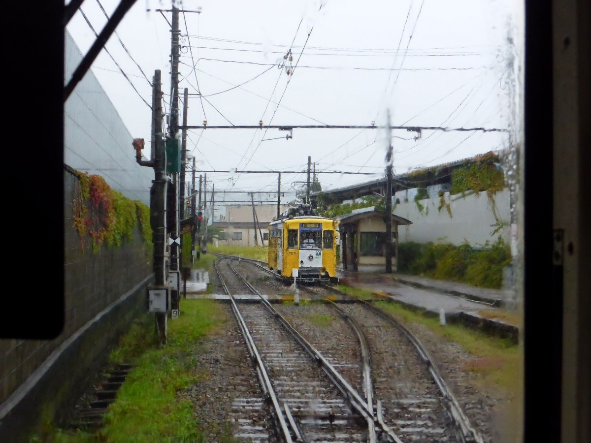 Takaoka Manyô-Linie, alte Wagen Serie 7070: Im strömenden Regen begegnet Wagen 7071 in Rokudôji, wo früher die Strassenbahnlinie endete und die Ueberlandlinie begann; heute ist der Betrieb durchgehend. 25.Oktober 2013. 