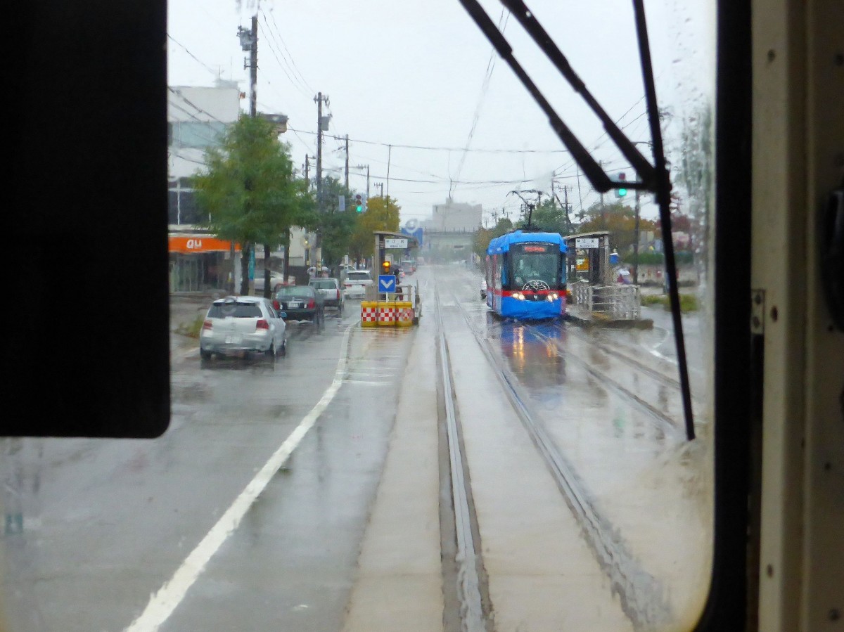 Takaoka Manyô-Linie, neue Wagen Serie 1000: Im peitschenden Regen begegnet der blaue 1002 in Ejiri, 25.Oktober 2013. 