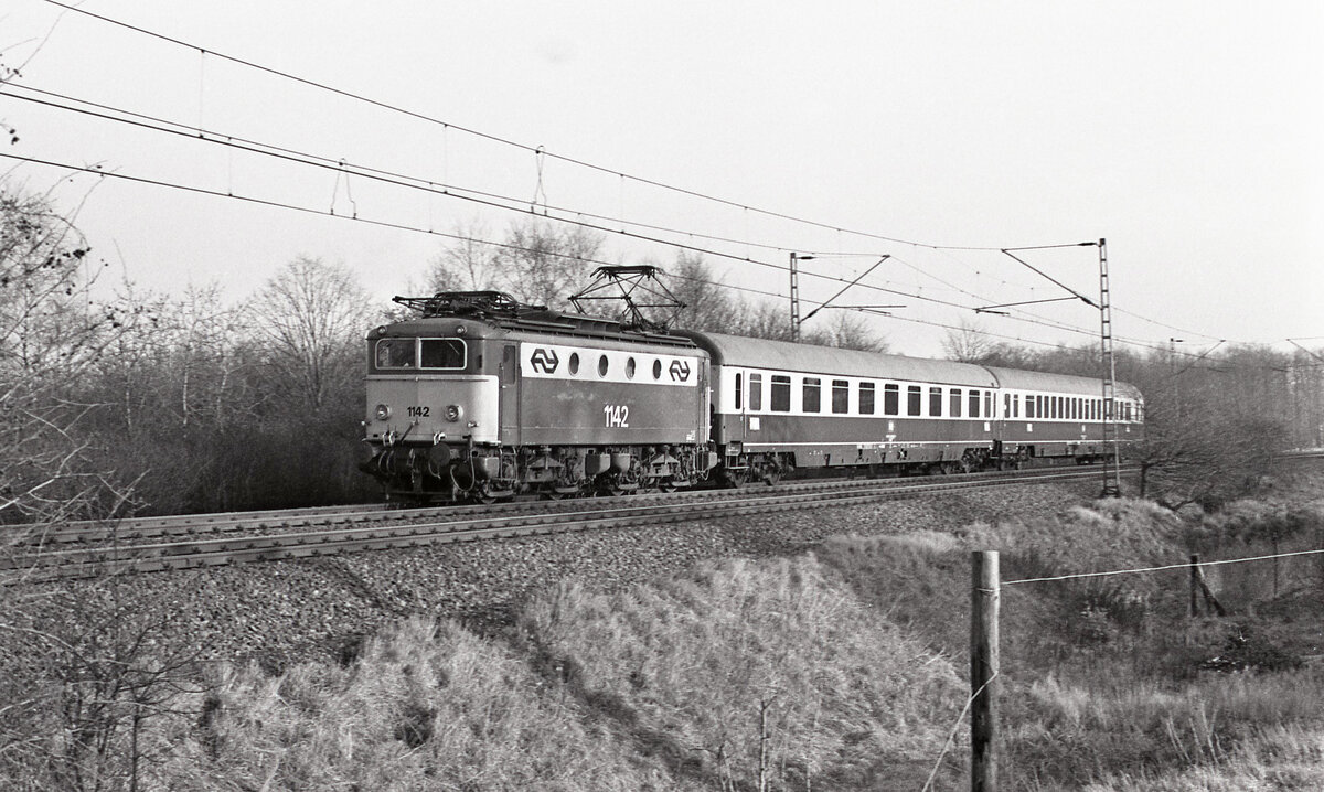 TEE-10  Rembrandt  (München Hbf - Amsterdam CS) mit NS 1142 bei Hüthum am 09.12.1976, ca 14.30u., km.65.2. Es wurde schnell gefahren da eine geringe Verspätung einzuholen war. Planmässig führt der Zug 1 Avm und 1 Apm; die anderen Wagengruppen blieben in Emmerich. Scan (Bild 90882, Kodak Tri-X Pan).
