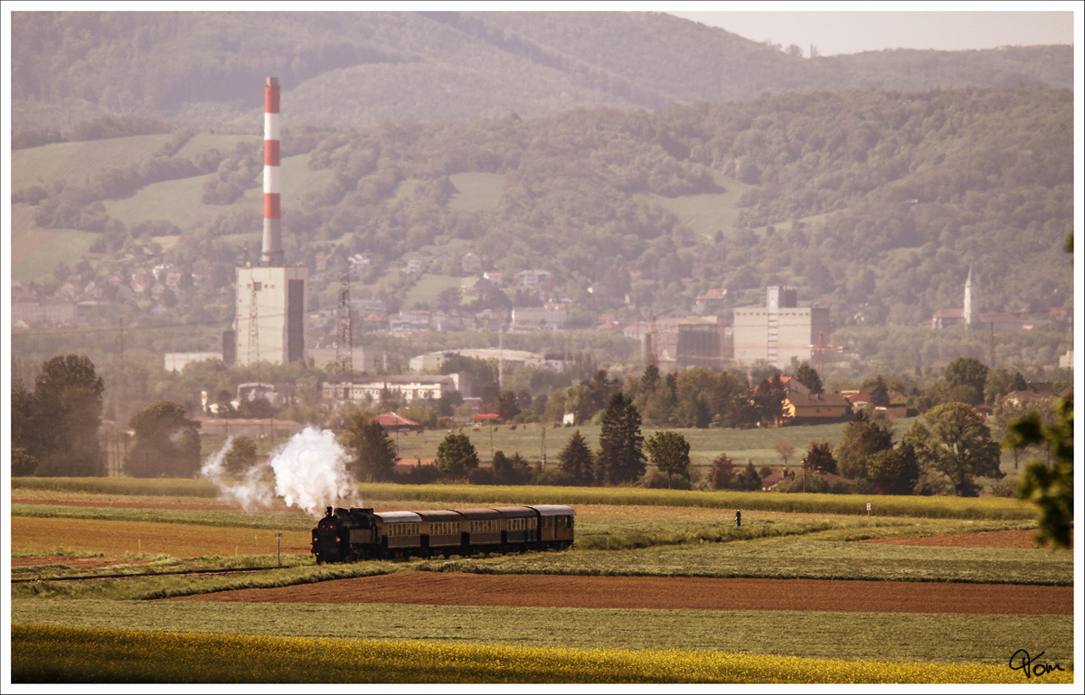 Teleaufnahme der 77.28, welche mit dem Erlebniszug  Leiser Berge  durch das Weinviertel dampft. Im Hintergrund die Stadt Korneuburg mit dem markanten Kraftwerk.
Mollmannsdorf 4.5.2014