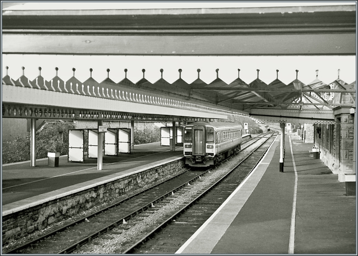 Tenby / Dinbich-y-pysgod ein kleiner Bahnhof einer walisischen Nebenbahn und doch so reich an Details... 
Ein Class 153 Triebwagen wartet auf dem Bahnsteig 2 auf die Abfahrt nach Swansae / Abertawe. 

Analogbild vom November 2000
