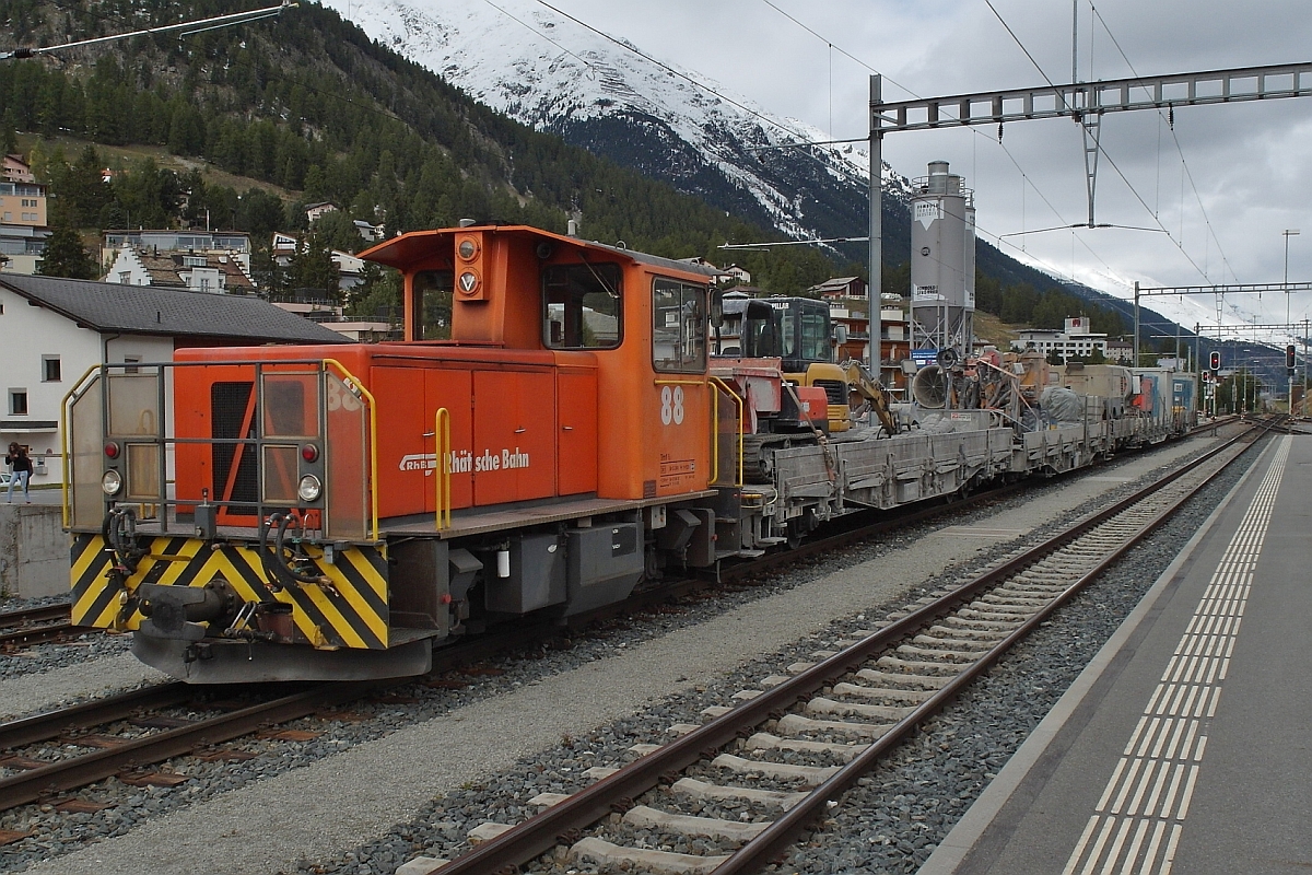 Tmf 2/2 88 hat einige Wagen eines Arbeitszuges mit unterschiedlichen Aggregaten und Maschinen vom Abstellgleis auf ein Durchfahrtsgleis im Bahnhof von Samedan rangiert (24.09.2015).