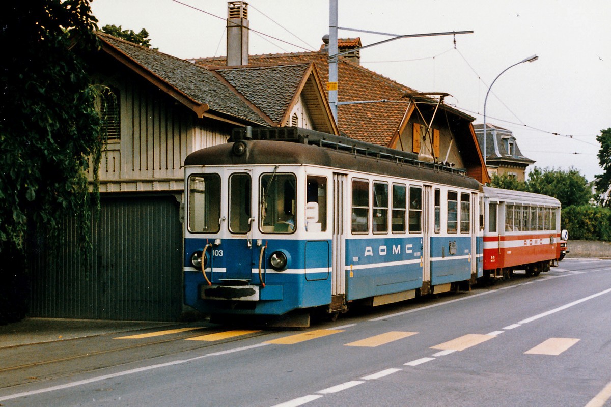 TPC/AOMC/BLT: Regionalzug Aigle-Monthey mit dem Be 4/4 103 (ehemals BTB) und einem B4 auf der alten Strassenbahnstrecke bei Aigle im August 1986. Noch immer trägt der Triebwagen 103 den blauen BLT/BTB Anstrich. Durch die Umstellung der BLT von Bahn- auf Strassenbahnbetrieb im Jahre 1984 wurden verschiedene BLT-Fahrzeuge überzählig. Ein grosser Teil dieser Motor- und Steuerwagen wurde damals von der ASD und der AOMC übernommen, wo sie nach diversen Anpassungen und Umlackierungen noch im Jahre 2015 im täglichen Einsatz stehen.
Foto: Walter Ruetsch