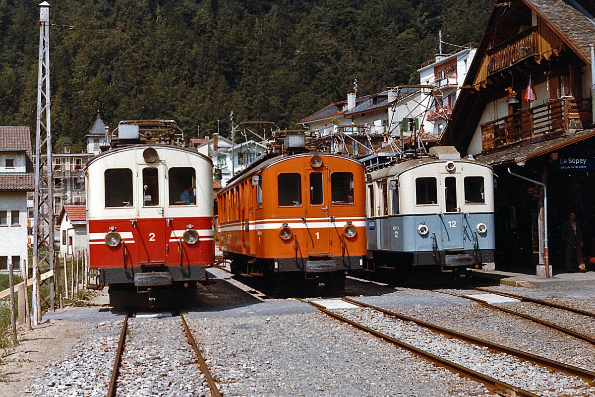 TPC/ASD: 100  Jahre ASD. Ueber das kommende Wochenende feiert die ASD ihren 100. Geburtstag. Zu diesem Anlass wird der restaurierte BCFe 4/4 1 im grau-weissen Anstrich mit Nostalgiezügen im Einsatz stehen. Farbenvielfalt auf der ASD. ABDe 4/4 2, ABDe 4/4 1 und ABFe 4/4 12 in Le Sépey im Juli 1984.
Foto: Walter Ruetsch