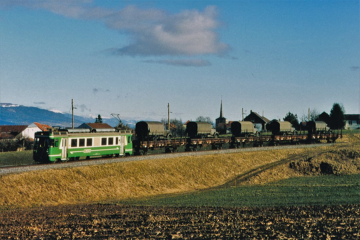 Transports de la région Morges-Bière-Cossonay, MBC/BAM.
Nicht erkennbarer Be 4/4 mit einem Militärzug in Richtung Bière unterwegs. Die Aufnahme entstand im Februar 1984 bei Ballens. Transportiert wurden fünf Armee-Lastwagen der Marken Saurer 2 DM und Berna 2 VM. In den Jahren 1964 bis 1976 wurden ca. 1'600 Saurer und 800 Berna beschafft. Ab dem Jahre 1998 wurden diese bei den Motorfahrern sehr beliebten Fahrzeuge durch Saurer 6 DM oder Steyr 5,6 t ersetzt.
Foto: Walter Ruetsch 