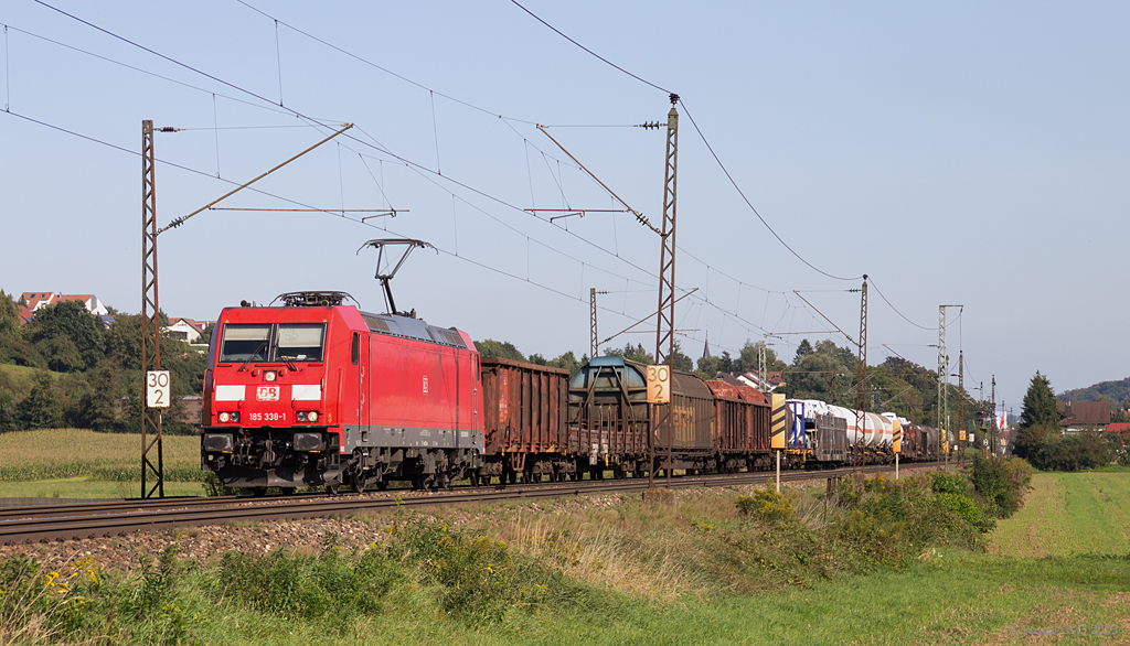 TRAXX-Power in Form von 185 338-1 gab es am 24. September 2013 auf der Filsbahn bei Ebersbach zu sehen. In Kontrast zur recht modernen Drehstromlok stehen die historischen Fahrleitungsmasten.