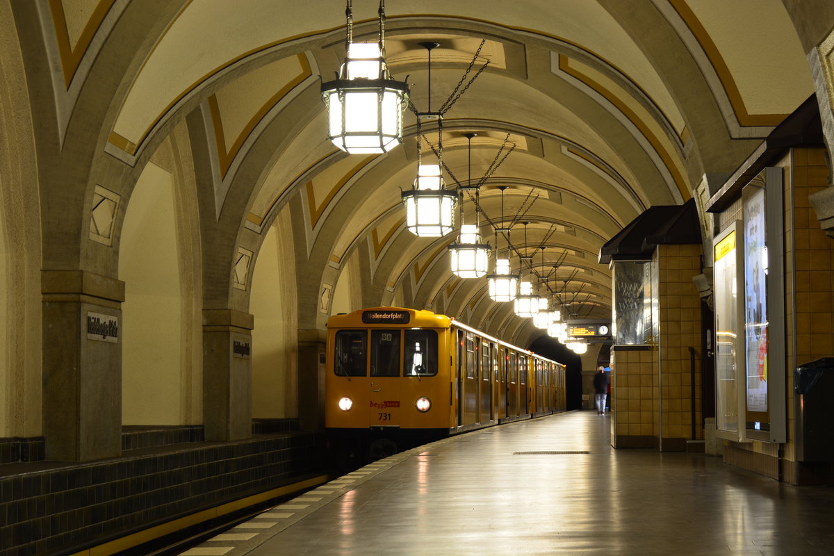 Triebzug 731 der Baureihe A3E Baujahre 1960 bis 1994 wartet in der am 12.Oktober 1913 eröffneten U-Bahn Station Heidelberger Platz auf Abfahrt. Da die Tunnelstrecke hier den Einschnitt der Ringbahn unterqueren musste, lag das Profil doppelt so tief wie beim Bau anderer U-Bahnhöfe. Das ermöglichte die hohen Deckengewölbe, die dem Bahnhof eine grandiose Raumwirkung geben. Gesteigert wird der Eindruck noch durch seine gekrümmte Lage.

Die Stadt Wilmersdorf als Bauherr der Bahn war bestrebt, mit der U-Bahn ihren Wohlstand auszudrücken, und veranlasste, dass alle Stationen auf dem Stadtgebiet keine stählernen, sondern steinerne Stützen aufweisen sollten. Die Bahnhöfe selbst unterscheiden sich grundsätzlich voneinander und beziehen sich nicht auf gleichwertige Merkmale wie Form und Ausstattung.

Im Falle des U-Bahnhofs Heidelberger Platz entwarf der zuständige Architekt Wilhelm Leitgebel einen Bahnhof, der einer Kathedrale ähnelt. Der Mittelbahnsteig wird zu beiden Enden von Vorhallen abgeschlossen, an die sich die Ausgänge anschließen. Die Decke des Bahnsteigs wurde als Kreuzgratgewölbe angelegt, was nur durch die besondere Tieflage ermöglicht wurde. Sämtliche Verkleidungen sind aus Stein sowie zum Teil aus Fliesen. 

Berlin Wilmersdorf 03.01.2018 


Seite „Bahnhof Berlin Heidelberger Platz“. In: Wikipedia, Die freie Enzyklopädie. Bearbeitungsstand: 6. November 2017, 21:17 UTC. URL: https://de.wikipedia.org/w/index.php?title=Bahnhof_Berlin_Heidelberger_Platz&oldid=170736034
