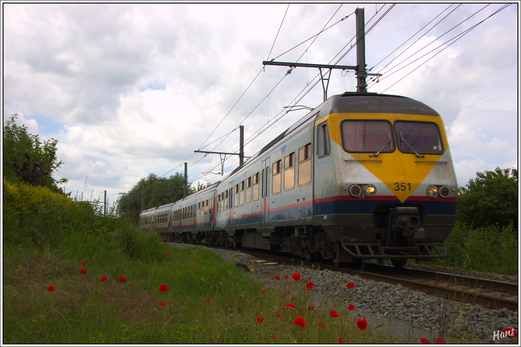 Triebzug AM 80 351, kommend aus Poperinge, fährt in den Bahnhof Ieper ein. Der Klatschmohn kommt in dieser Gegend viel vor, und hat eine wichtige Rolle bekommen beim Gedenken der Opfer des Ersten Weltkrieges.