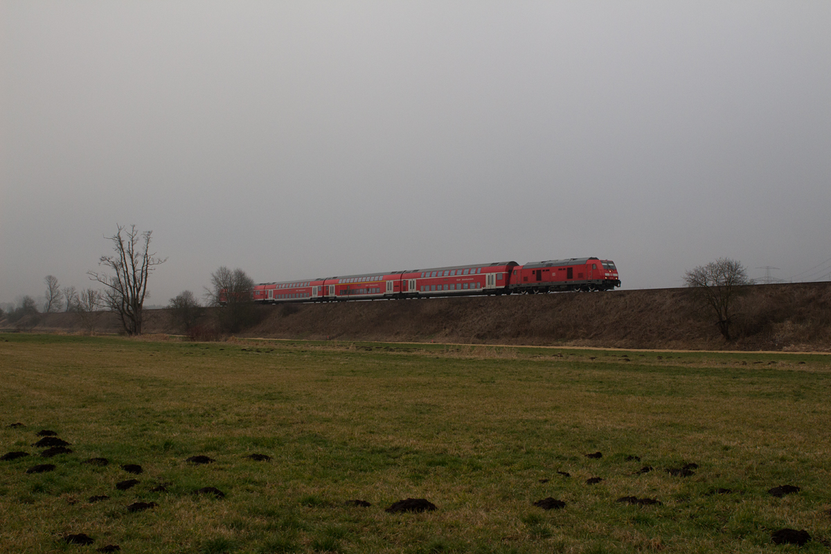 Trüb, grau und naßkalt geht das Jahr 2015 in Oberbayern zu Ende. Am Sylvestertag wurde eine 245 mit ihrem Doppelstockzug von München Hbf nach Mühldorf bei Markt Schwaben fotografiert.

So allmählich sieht man den Loks äußere Betriebsspuren an, ihr Lack glänzt nicht mehr so neu.