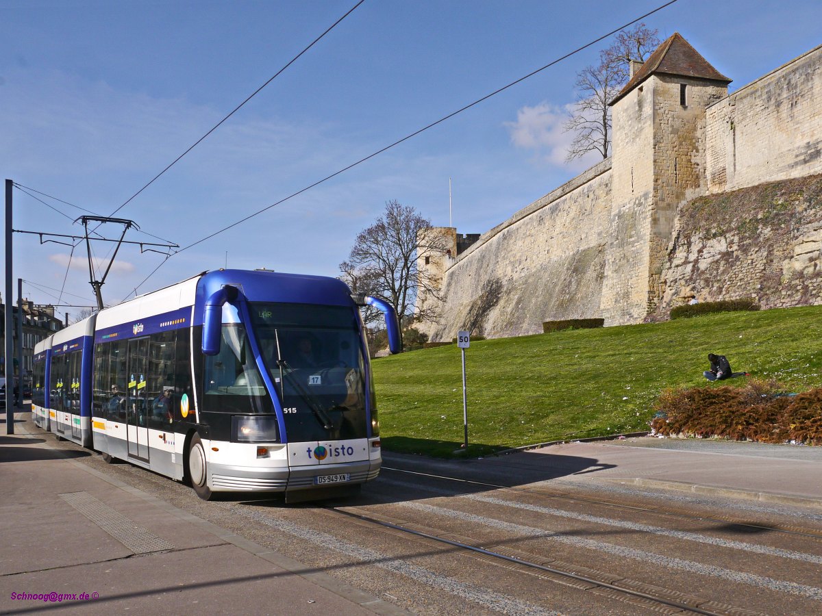 TVR Twisto-515 unterwegs vor der Burgmauer als Ligne-A nach Ifs-Jean-Vilar.
Zu Zeiten von Wilhelm dem Eroberer war Caen das Zentrum des normannischen Reichs. Er ließ die Burg zur damals größten Europas ausbauen. Auch wenn im Laufe der Jahrhunderte viel zerstört wurde, beeindruckt ihre Größe auch heute noch.
Seit 2002 fahren in Caen die spurgeführten Obusse des Systems TVR (Transport sur voie réservée). Anfang 2018 wird das System eingestellt und in ein konventionelles Straßenbahnsystem umgebaut, welches 2019 in Betrieb gehen soll.

2016-02-27 Caen Rue-de-Geôle 