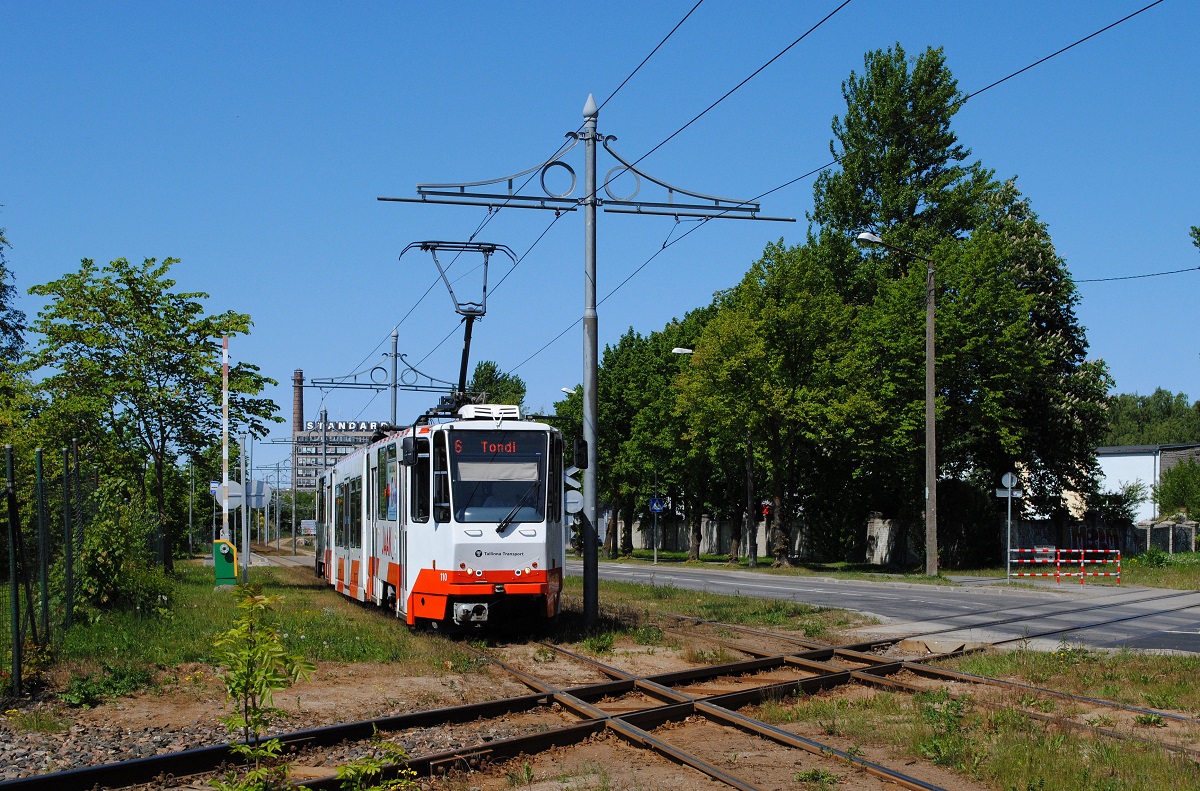 Tw. 110 überquert in der Kopli die mittels Schrankenanlage gesicherte Bahnübersetzung der Anschlußbahn zum Hafen. (07.06.2023)