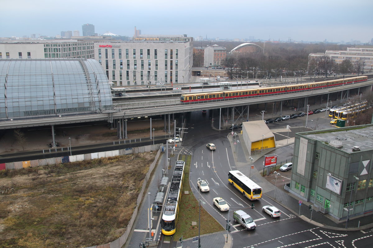 Über den Dächern Berlins. 
Während eine Tram ihre Fahrt antritt fährt eine S-Bahn gen Westen. 

Berlin Hbf, 14. Dezember 2016